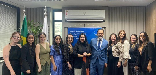 Desembargador Ramom Tácio e Alê Portela posam para foto, junto com outras nove mulheres.