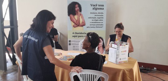 Foto mostra uma servidora colhendo as digitais de uma eleitora.