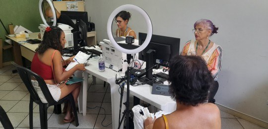 Foto mostra duas mulheres sendo atendidas por servidoras do TRE-MG