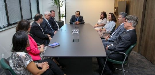 Foto com dez pessoas sentadas em torno de uma mesa de reuniões