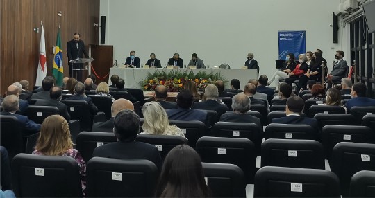 Desembargador Alexandre Carvalho discursa para pessoas sentadas na plateia de um auditório. No p...