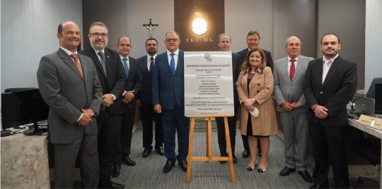 Integrantes da Corte Eleitoral mineira posam ao redor de uma placa posicionada em um cavalete.