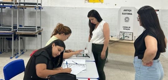 Foto mostra duas eleitoras e duas mesárias em uma seção eleitoral