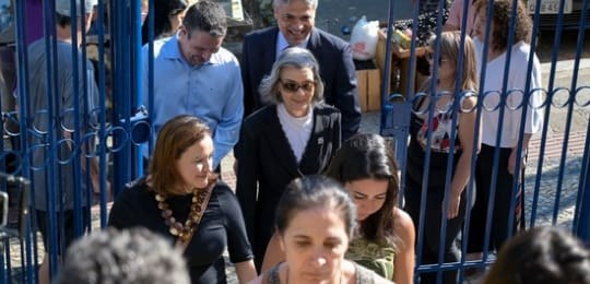 Ministra Cármem Lúcia entrando no local de votação, cercada d algumas pessoas